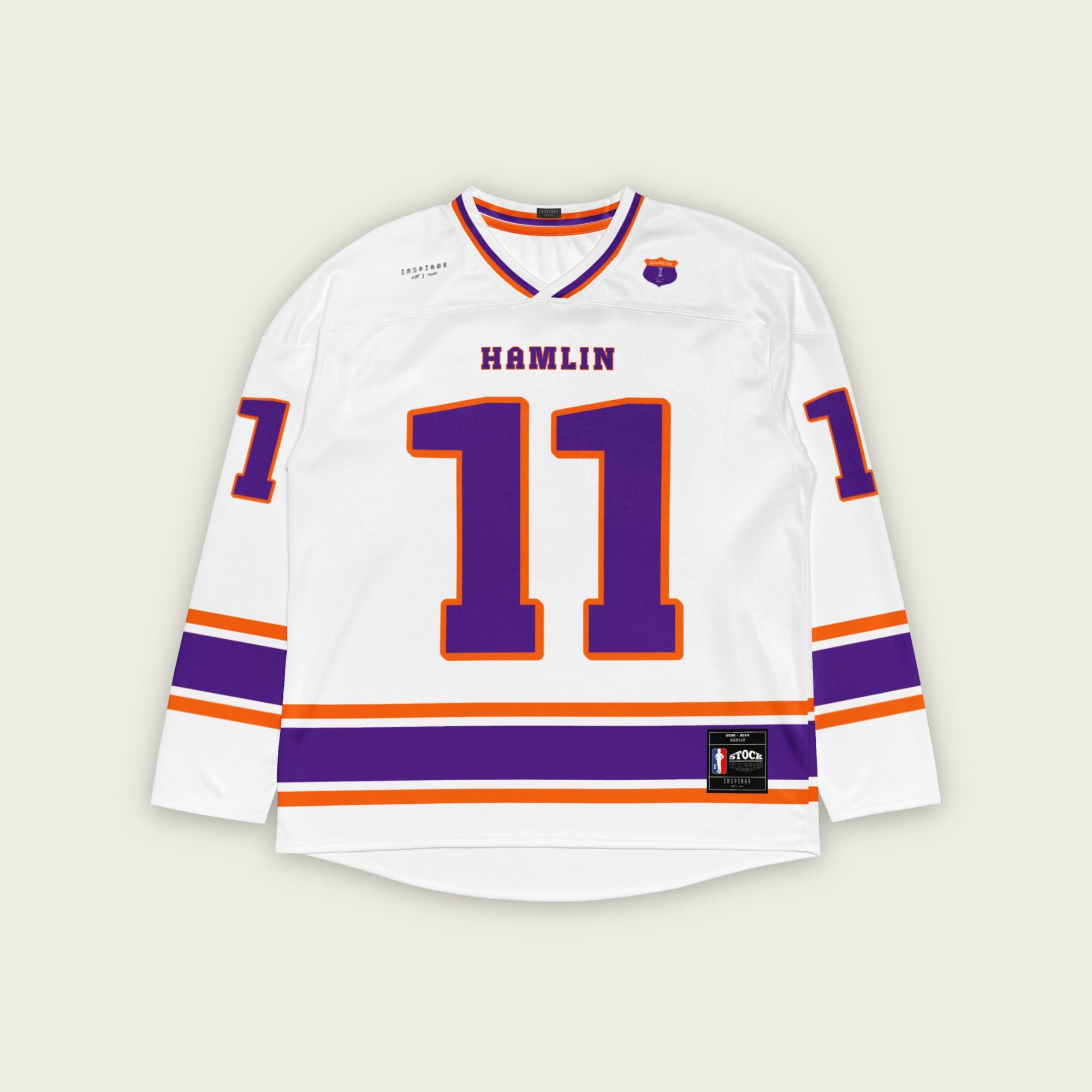 A white hockey jersey with three stripes at the bottom, the middle line is purple and other two are orange. There is Denny Hamlin's nascar number 11 on the front and back in purple with a orange outline. Denny Hamlin's last name is on the back and front as well.