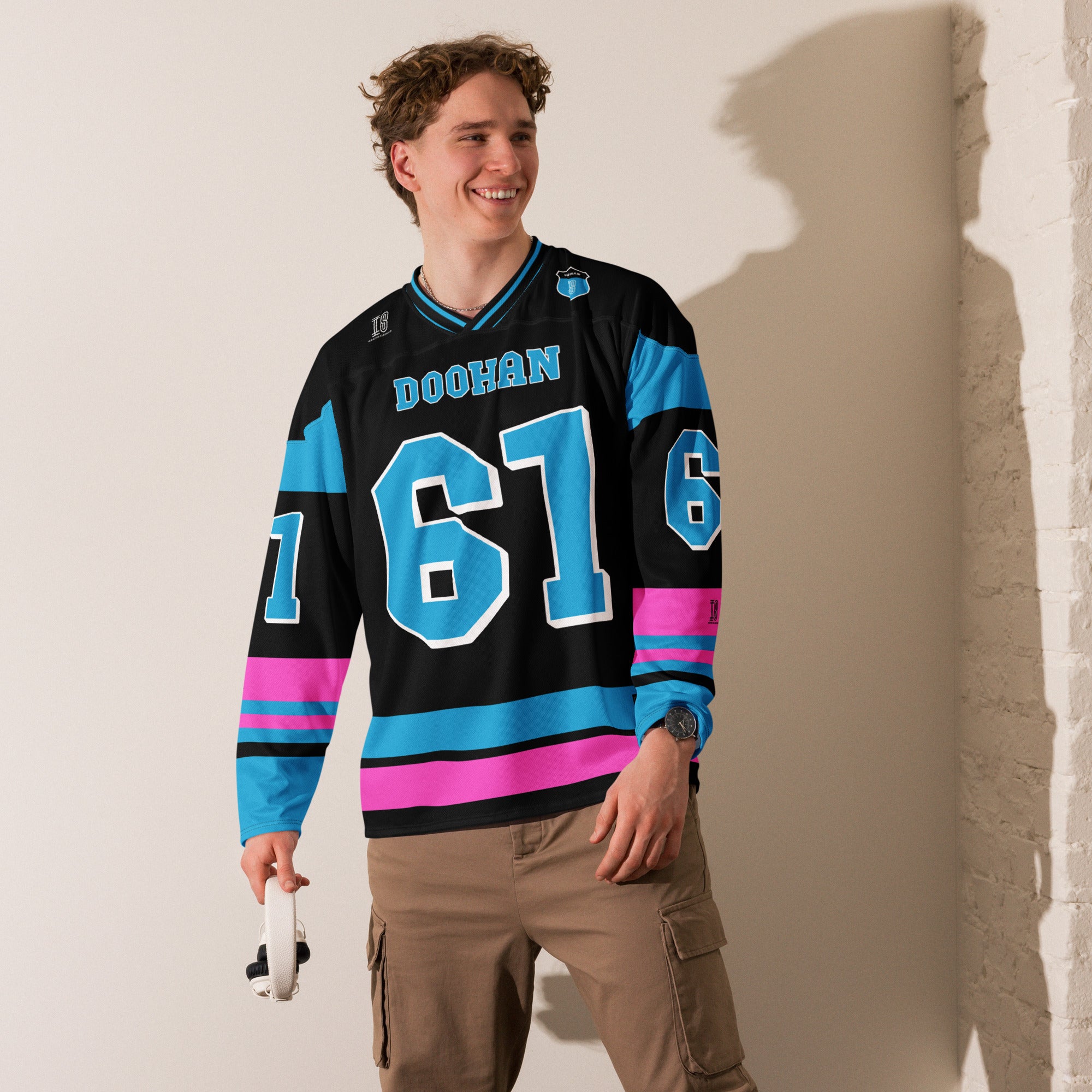 A black, blue, and pink hockey jersey with Jack Doohan's F1 2025 Alpine racing number 61 on the front and back in blue. The name Doohan in blue is on the front and back.
