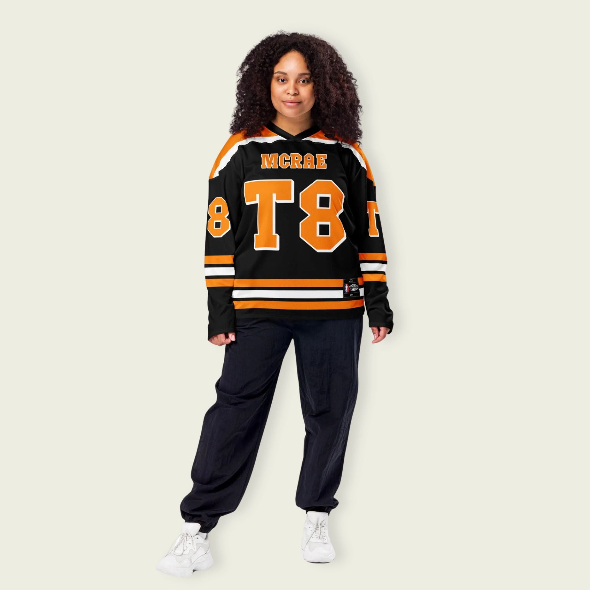 A black, orange, and white hockey jersey with the name Mcrae in orange on the front and back. Also T8 in orange on the front and back.